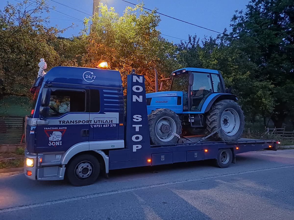 Platformă Tractări Auto Baia Mare – Joni transportând un tractor pe drum